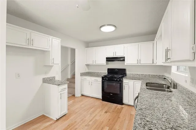 a kitchen with granite countertop a sink stove and refrigerator