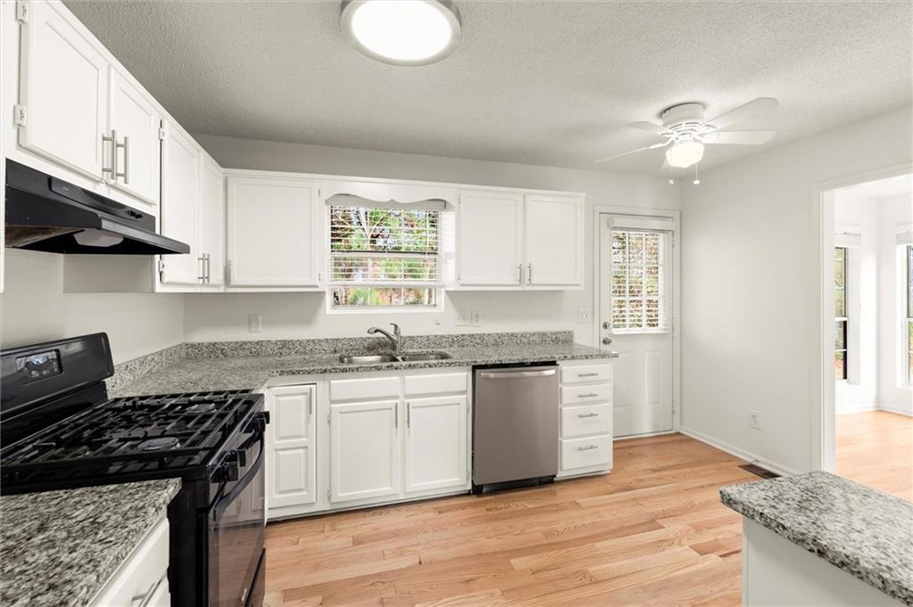 5984 Brookside Court Southeast Mableton, GA 30126 - Photo 8 of 21 a kitchen with granite countertop a sink cabinets stainless steel appliances and a window