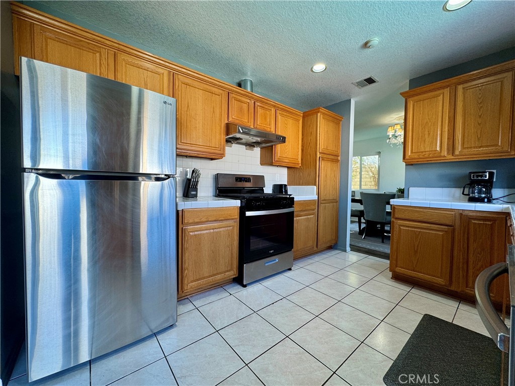 21 North Slope Lane Pomona, CA 91766 - Photo 12 of 48 a kitchen with a refrigerator a stove top oven a sink dishwasher and wooden cabinets