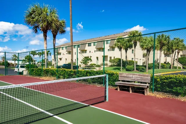 a view of a tennis court with a house in the background