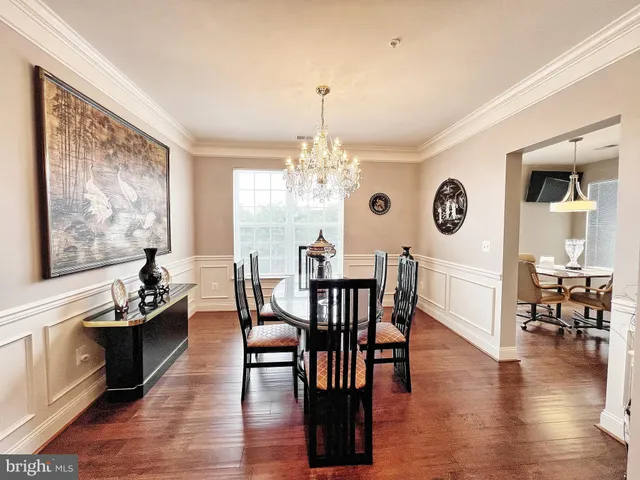 a dining room with wooden floor a chandelier a wooden table and chairs