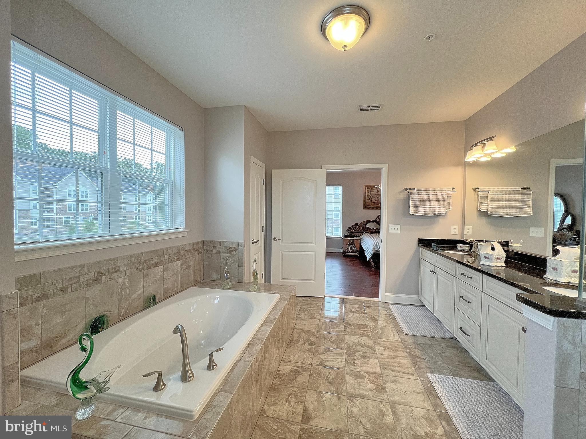 605 Quarry View Court, Unit 307 Reisterstown, MD 21136 - Photo 22 of 30 a large spacious bathroom with a granite countertop tub and a large window