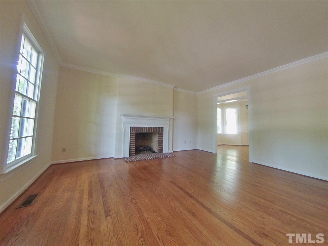 3312 Wade Avenue Raleigh, NC 27607 - Photo 3 of 13 an empty room with wooden floor fireplace and windows