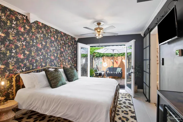 a bedroom with a large bed a flat tv screen and a dresser