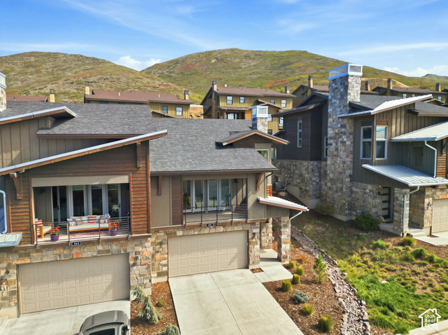 369 East Overlook Loop Kamas, UT 84036 - Photo 6 of 64 Multi-story residence featuring a stone and wood siding exterior, attached two-car garage, and a balcony with metal railings