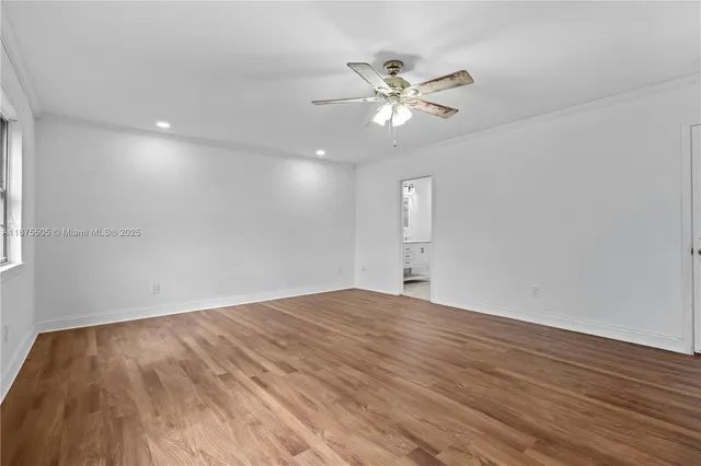 a view of an empty room with wooden floor and chandelier fan