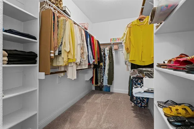 a view of walk in closet with clothes and shoes