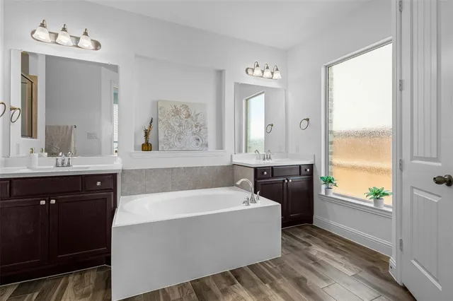 a bathroom with a tub a sink and a window