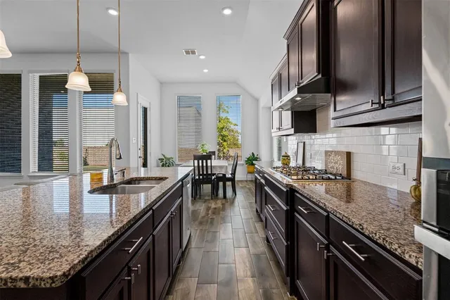an open kitchen with granite countertop lots of counter top space a sink and stainless steel appliances
