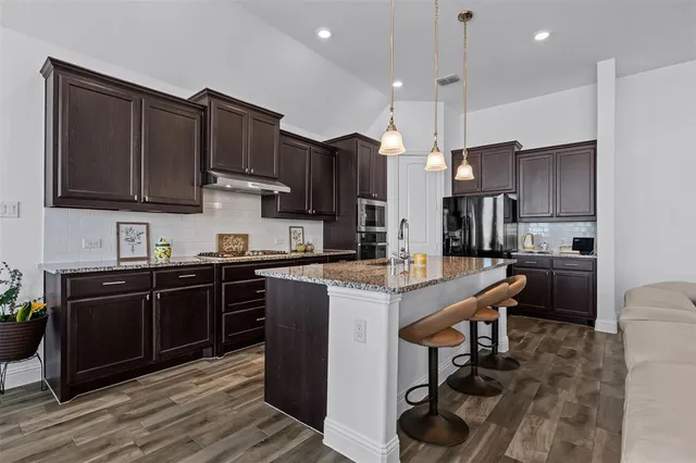 a kitchen with stainless steel appliances granite countertop a sink stove and refrigerator