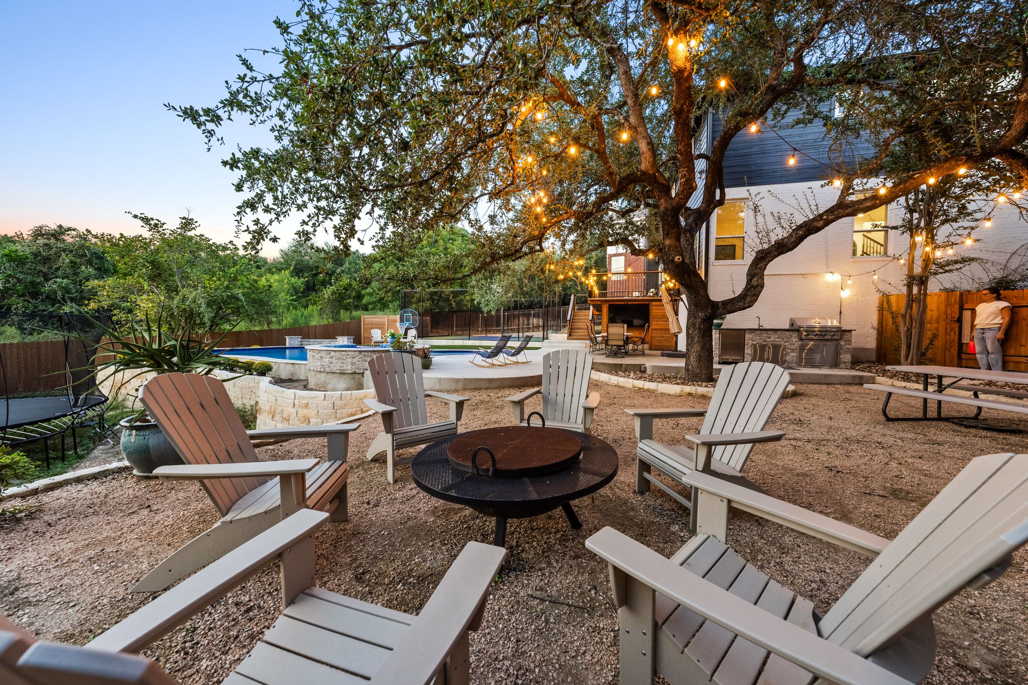 2204 Rimrock Drive Austin, TX 78738 - Photo 2 of 39 Mature trees shade a gravel courtyard leading to a swimming pool and outdoor kitchen.
