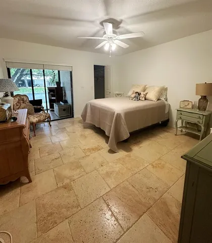 a spacious bedroom with a bed a table chair and glass door