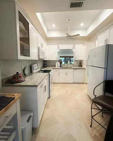 a kitchen with a refrigerator a stove a sink dishwasher and white cabinets with wooden floor
