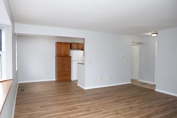 a view of an empty room with wooden floor and closet