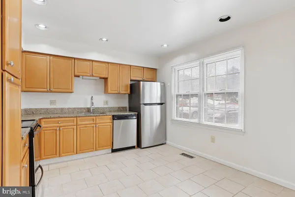 a kitchen with granite countertop white cabinets and refrigerator