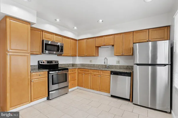 a kitchen with granite countertop a refrigerator stove top oven a sink and dishwasher