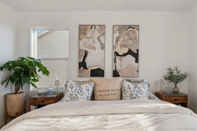 a bedroom with a large bed and a potted plant