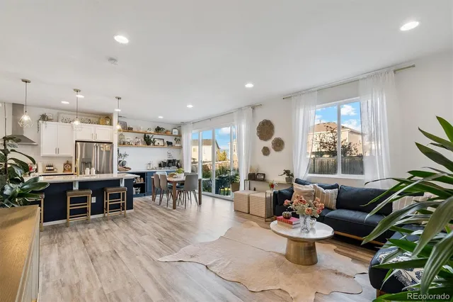 a living room with furniture kitchen view and a large window