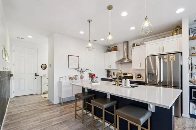 a kitchen with kitchen island a sink stove and refrigerator with wooden floor