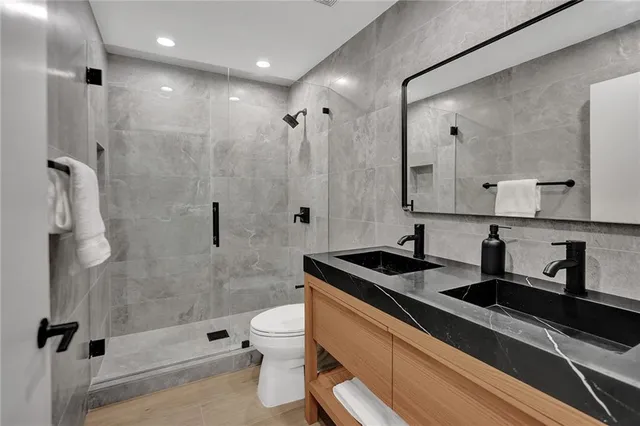 a bathroom with a granite countertop sink a toilet and shower