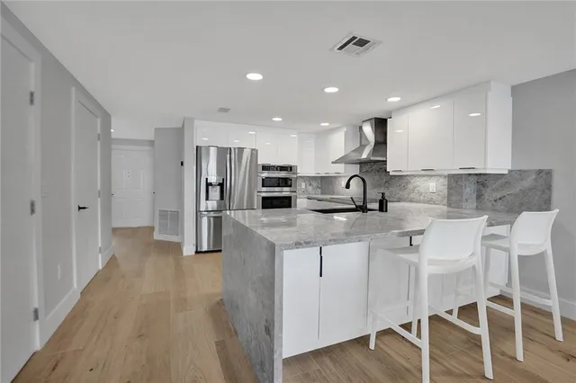 a kitchen with stainless steel appliances granite countertop a refrigerator and a stove top oven