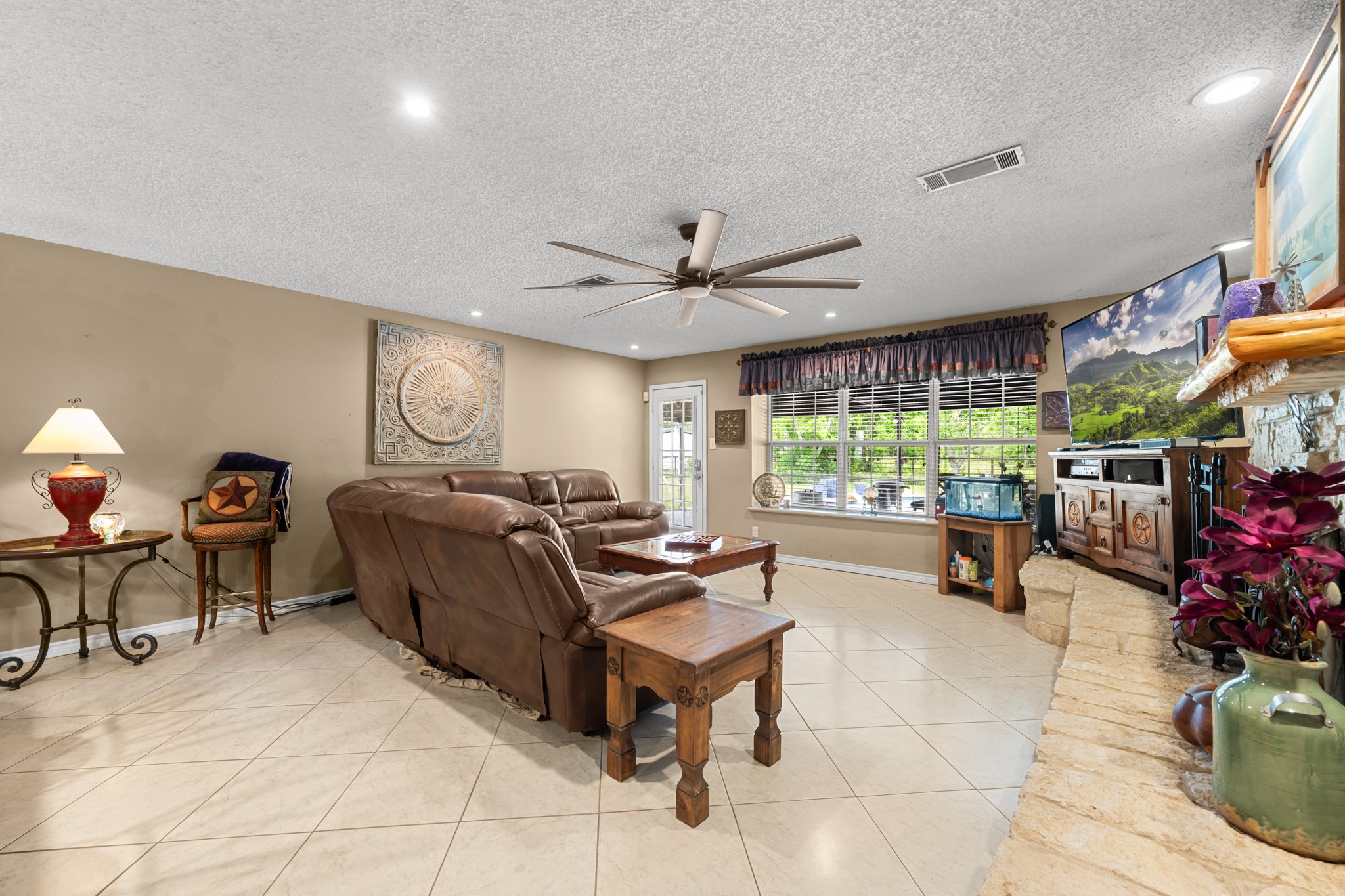 15602 Fir Road Santa Fe, TX 77517 - Photo 14 of 42 Spacious open living room featuring a beautiful stone fireplace, recessed lighting, and oversized windows overlooking the property. The expansive layout and neutral finishes provide the perfect setting for everyday living and entertaining alike.