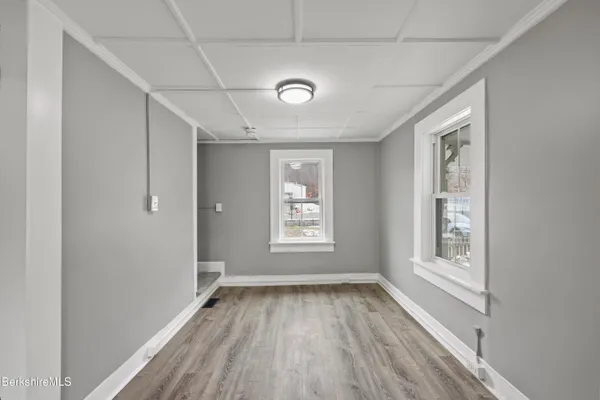 a view of an empty room with a window and wooden floor