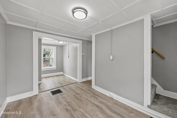 a view of empty room with wooden floor and fan