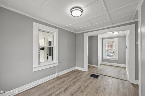 an empty room with wooden floor and windows