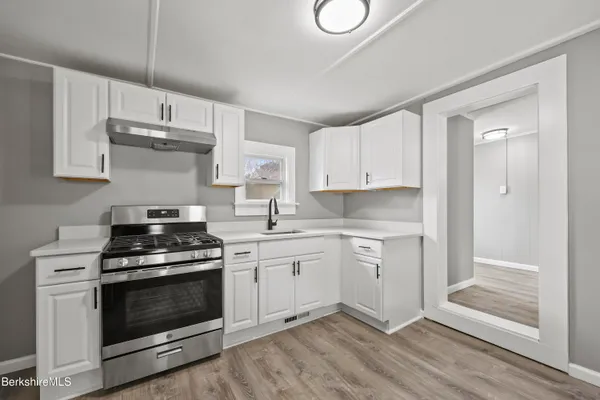 a kitchen with cabinets stainless steel appliances and wooden floor