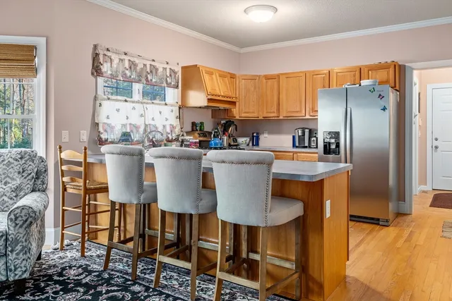 a kitchen with stainless steel appliances a dining table chairs refrigerator and sink