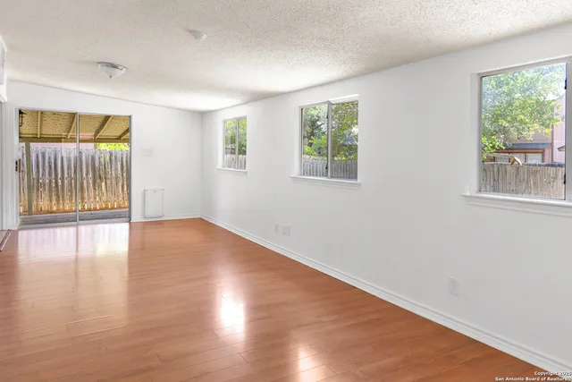 an empty room with wooden floor and windows