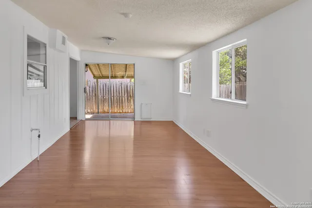 an empty room with wooden floor and windows