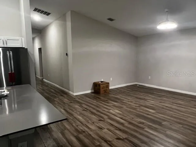 a view of a refrigerator in kitchen and an empty room