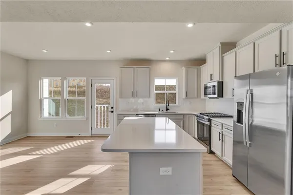 a large kitchen with kitchen island a large window a sink and stainless steel appliances