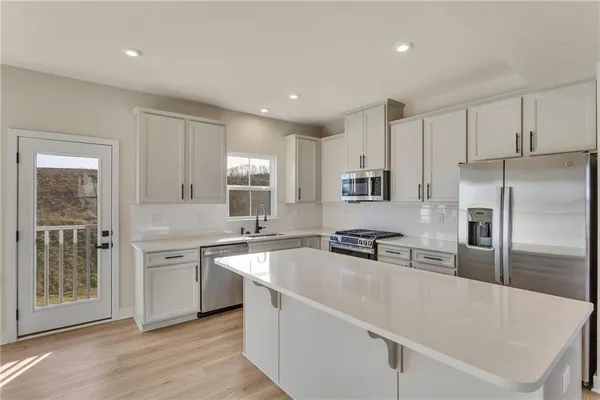 a kitchen with stainless steel appliances granite countertop a sink a stove a refrigerator and cabinets