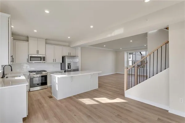 a large white kitchen with wooden floors stainless steel appliances and white cabinets