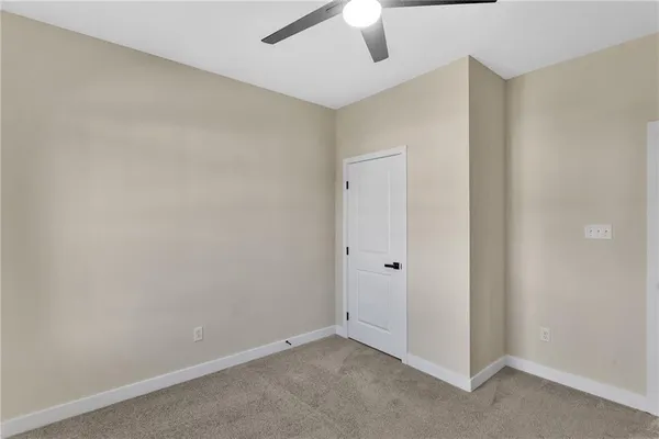 an empty room with a ceiling fan and carpet