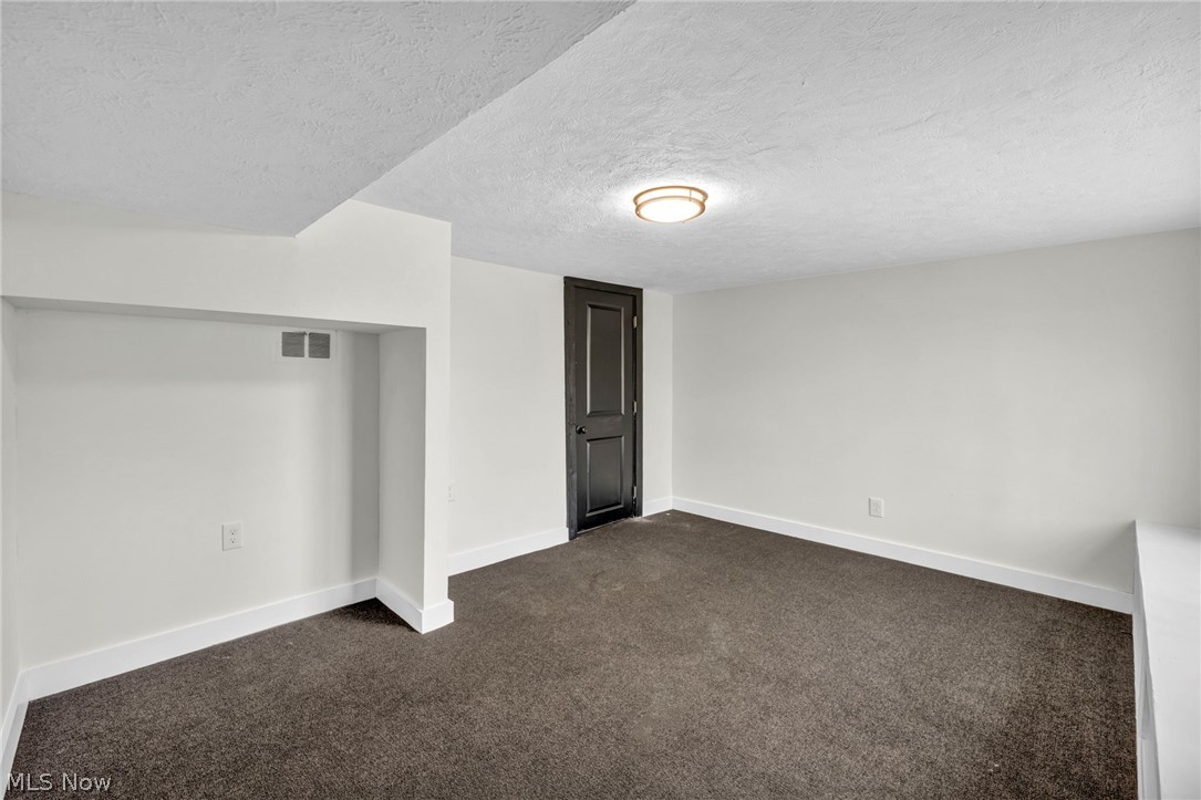 7339 River Road Olmsted Falls, OH 44138 - Photo 37 of 45 Room featuring dark carpet, white baseboards, and a contrasting dark door