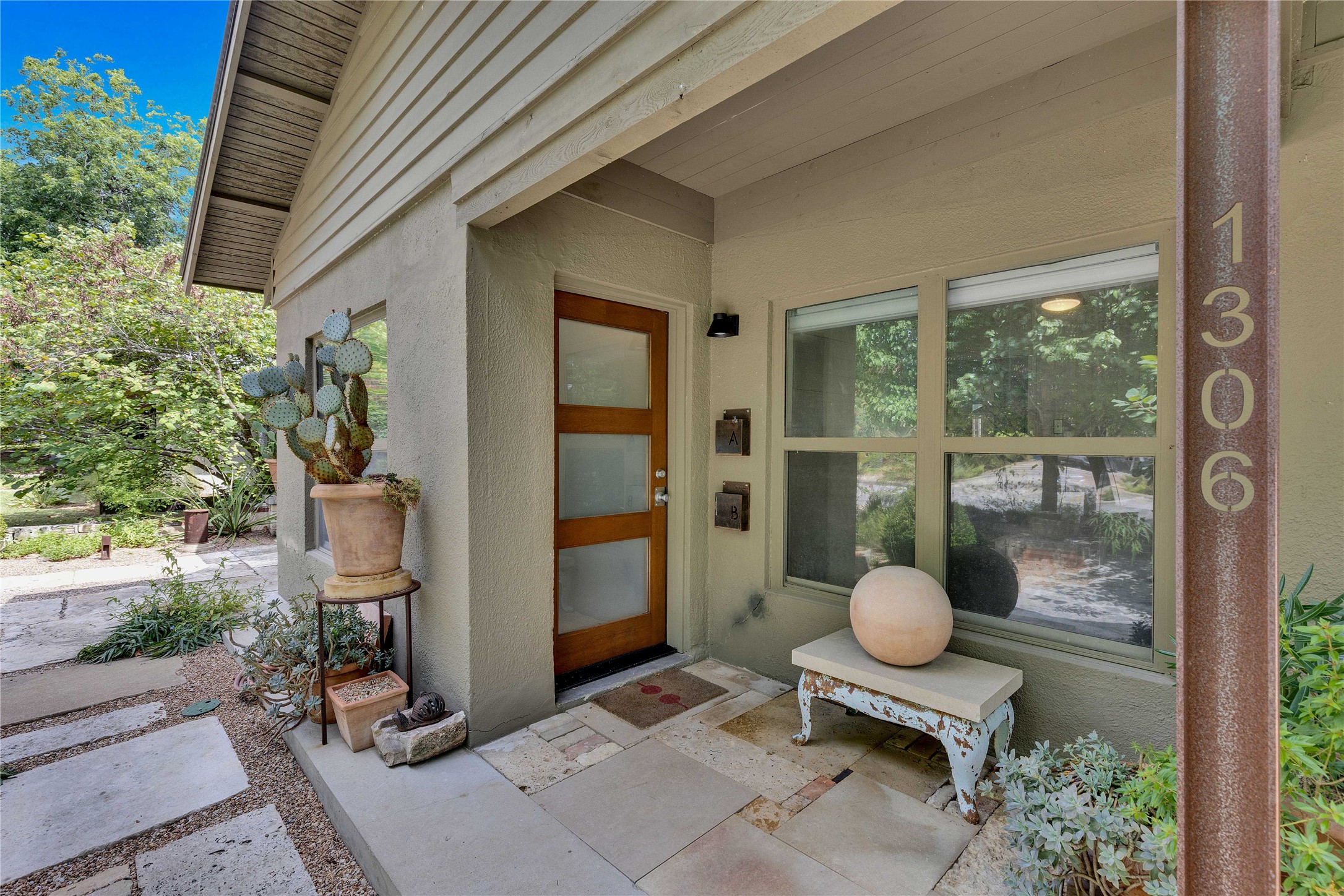 1306 Norwood Road, Unit A Austin, TX 78722 - Photo 5 of 21 A welcoming front entrance featuring natural wood and frosted glass, complemented by diverse plant life.