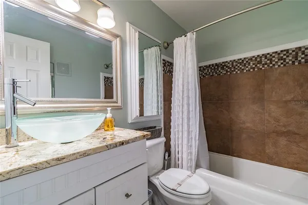 a bathroom with a granite countertop bathtub sink vanity mirror and toilet