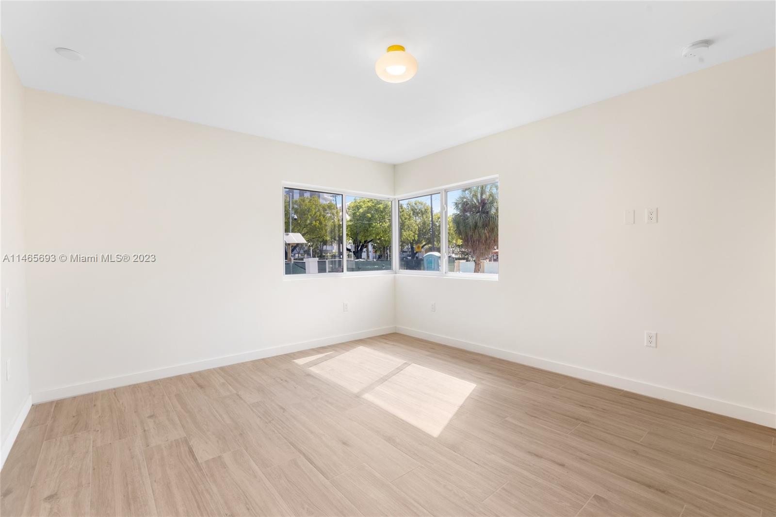 4160 Alton Road Miami Beach, FL 33140 - Photo 17 of 34 an empty room with wooden floor and windows