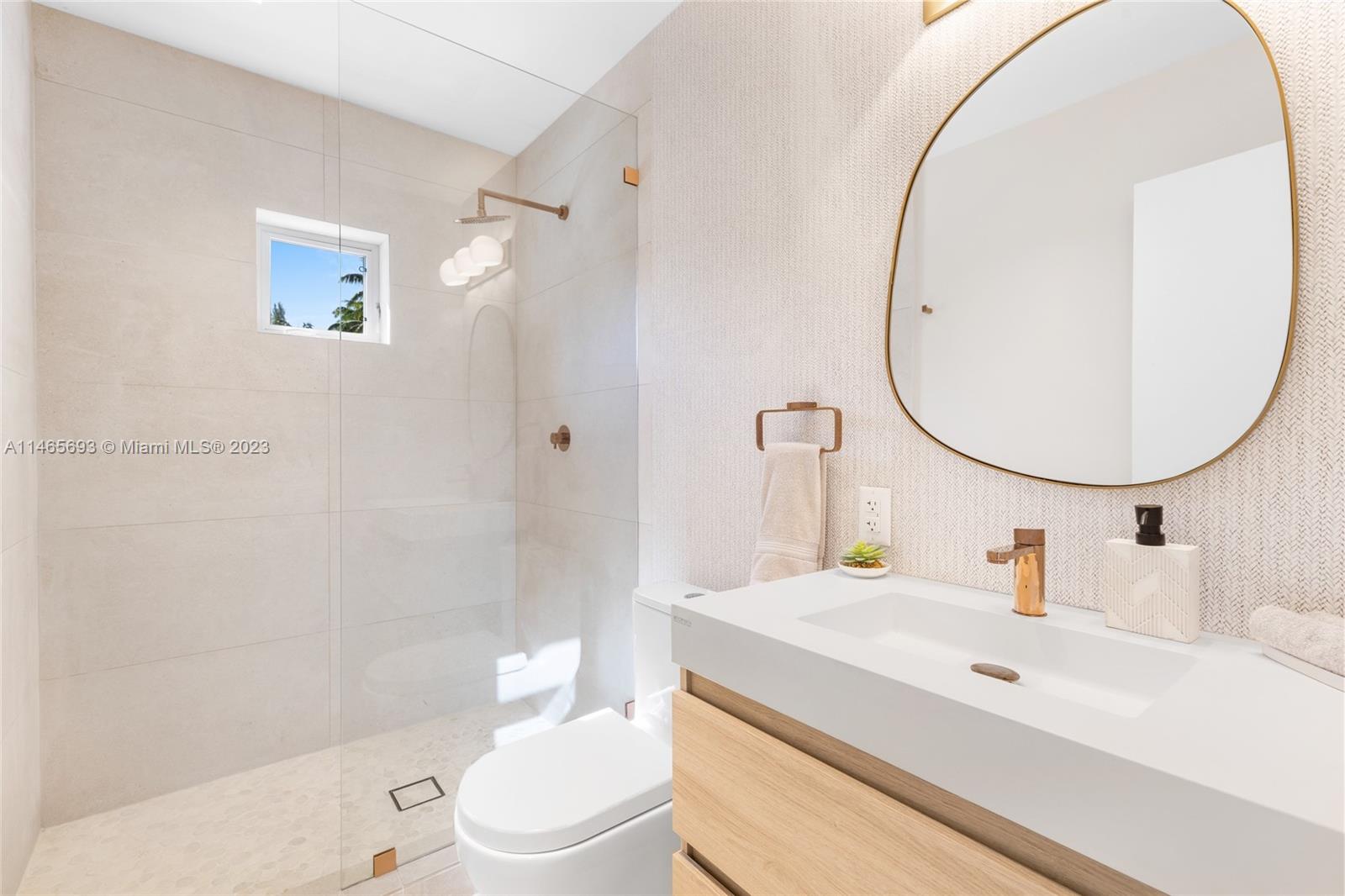 4160 Alton Road Miami Beach, FL 33140 - Photo 19 of 34 a bathroom with a sink a mirror a toilet and a shower