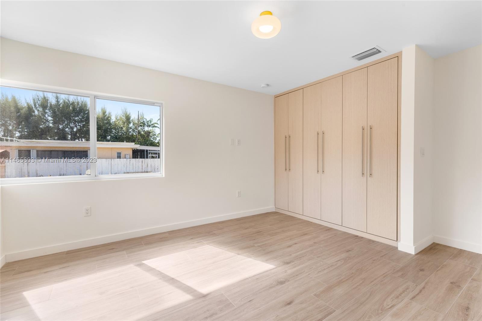 4160 Alton Road Miami Beach, FL 33140 - Photo 21 of 34 an empty room with wooden floor and windows
