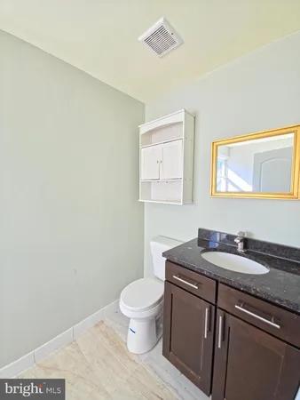 a bathroom with a granite countertop sink a toilet and a mirror