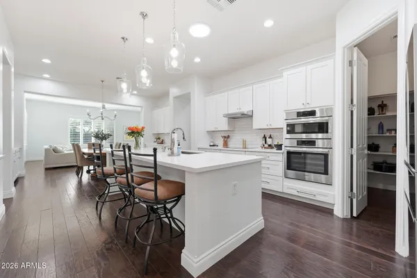 a kitchen with stainless steel appliances a table chairs wooden floors and a view of living room