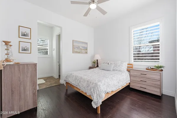 an empty room with wooden floor chandelier fan and windows