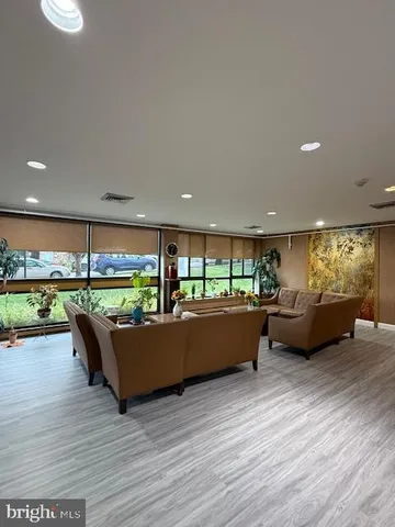 a living room with furniture floor to ceiling window and a wooden floor