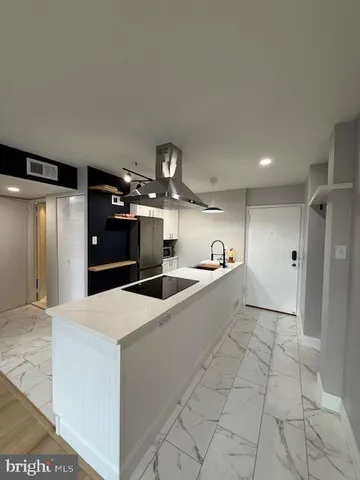 a large white kitchen with a sink and refrigerator