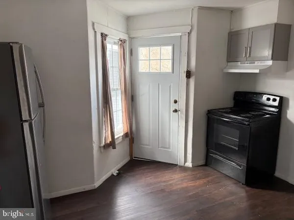 a view of an empty room and wooden floor in a kitchen